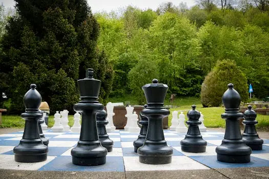 Giant chess pieces on a board outdoors surrounded by greenery in Bad Liebenzell, Germany.