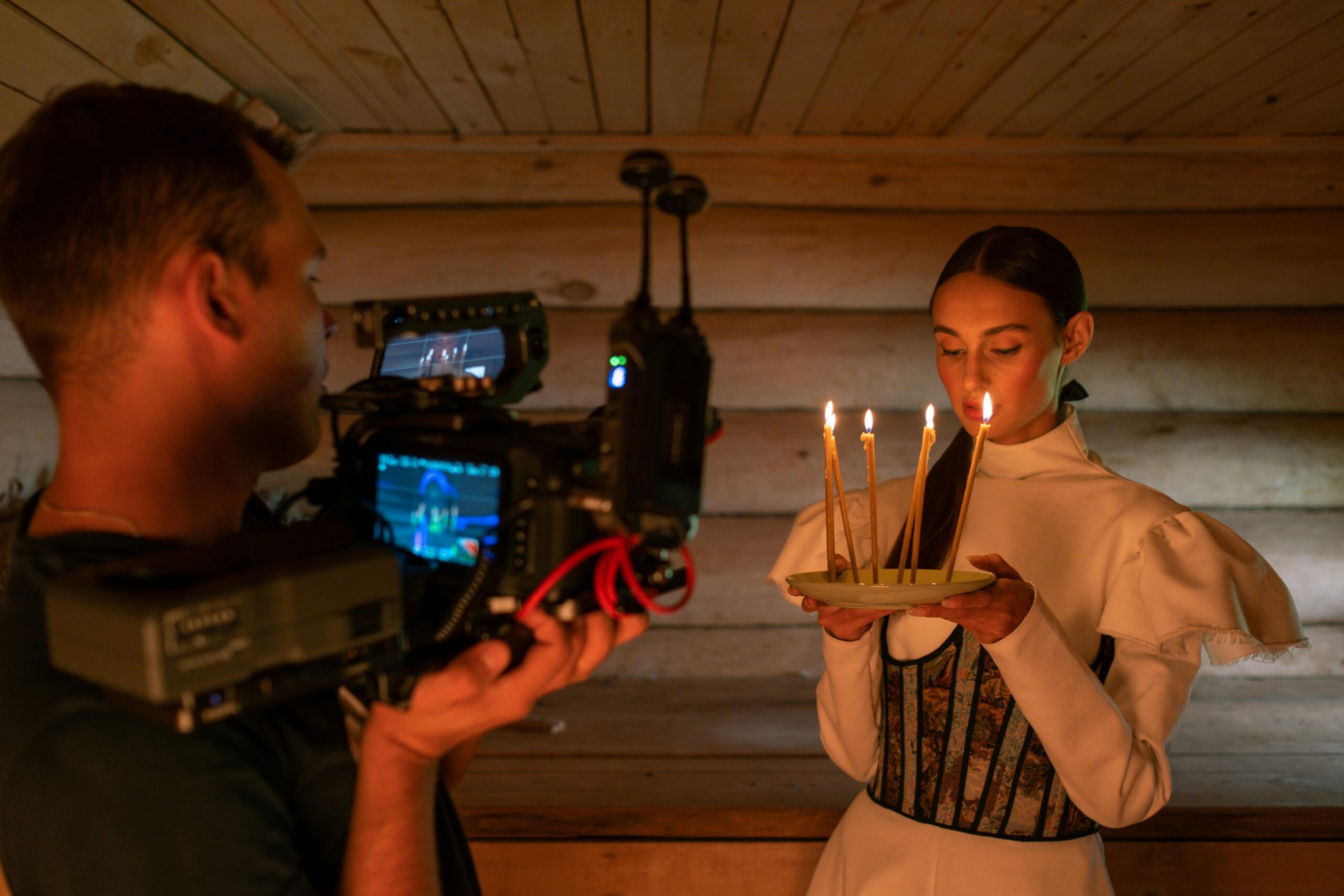 A filmmaker captures a woman holding candles in a dramatic indoor setting.