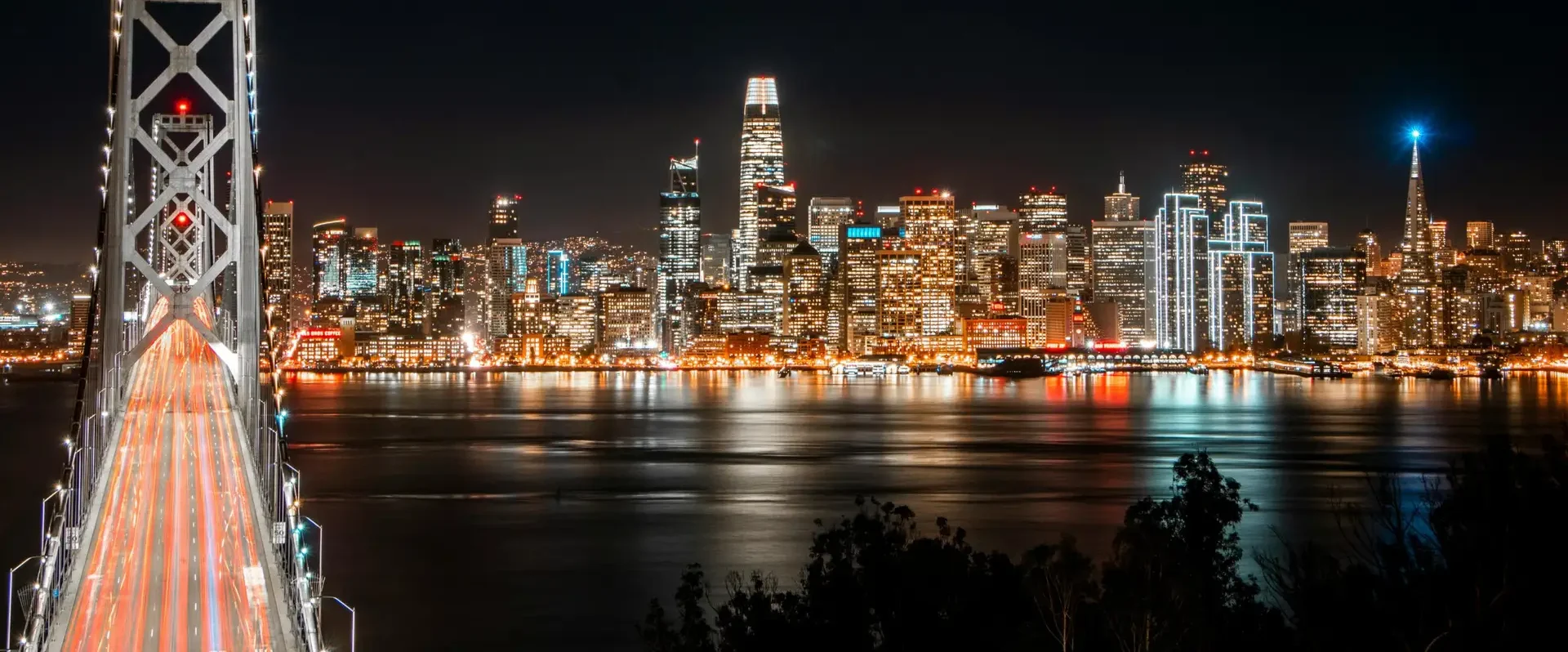 Stunning view of San Francisco skyline and Bay Bridge illuminated at night.