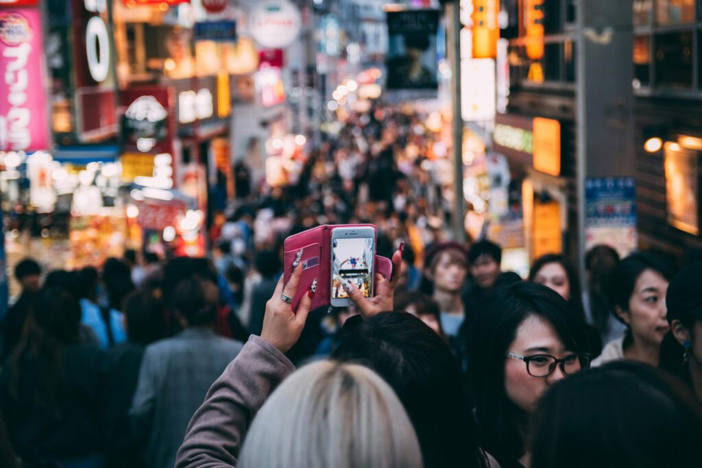 Vibrant street scene in a busy city market with diverse crowds and bright neon signage.