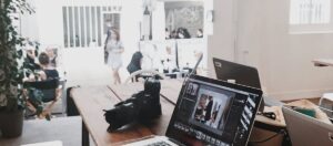 A bright, modern workspace featuring laptops, a camera, and a drawing tablet in an indoor office.